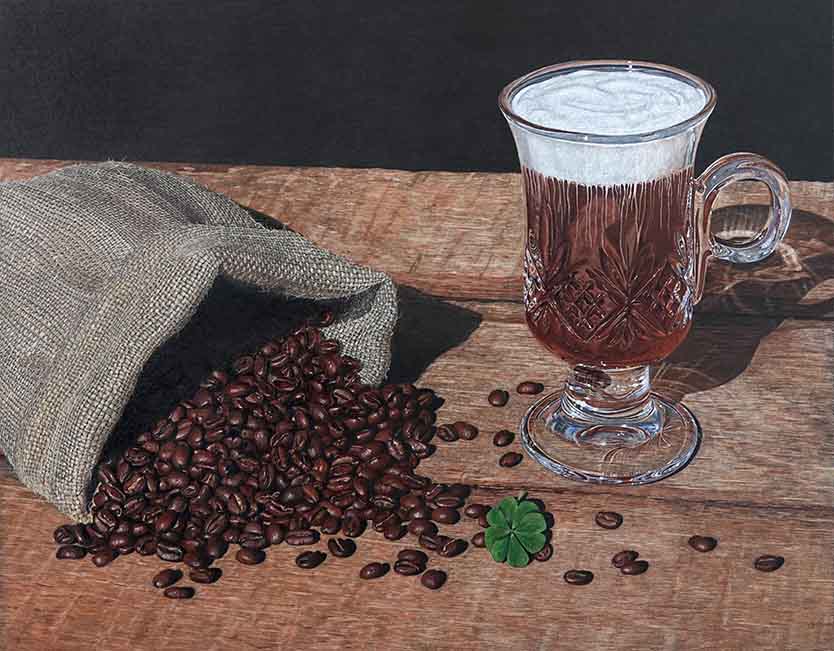 Coffee beans spilling from a burlap bag beside a mug of Irish Coffee and a four leaf clover